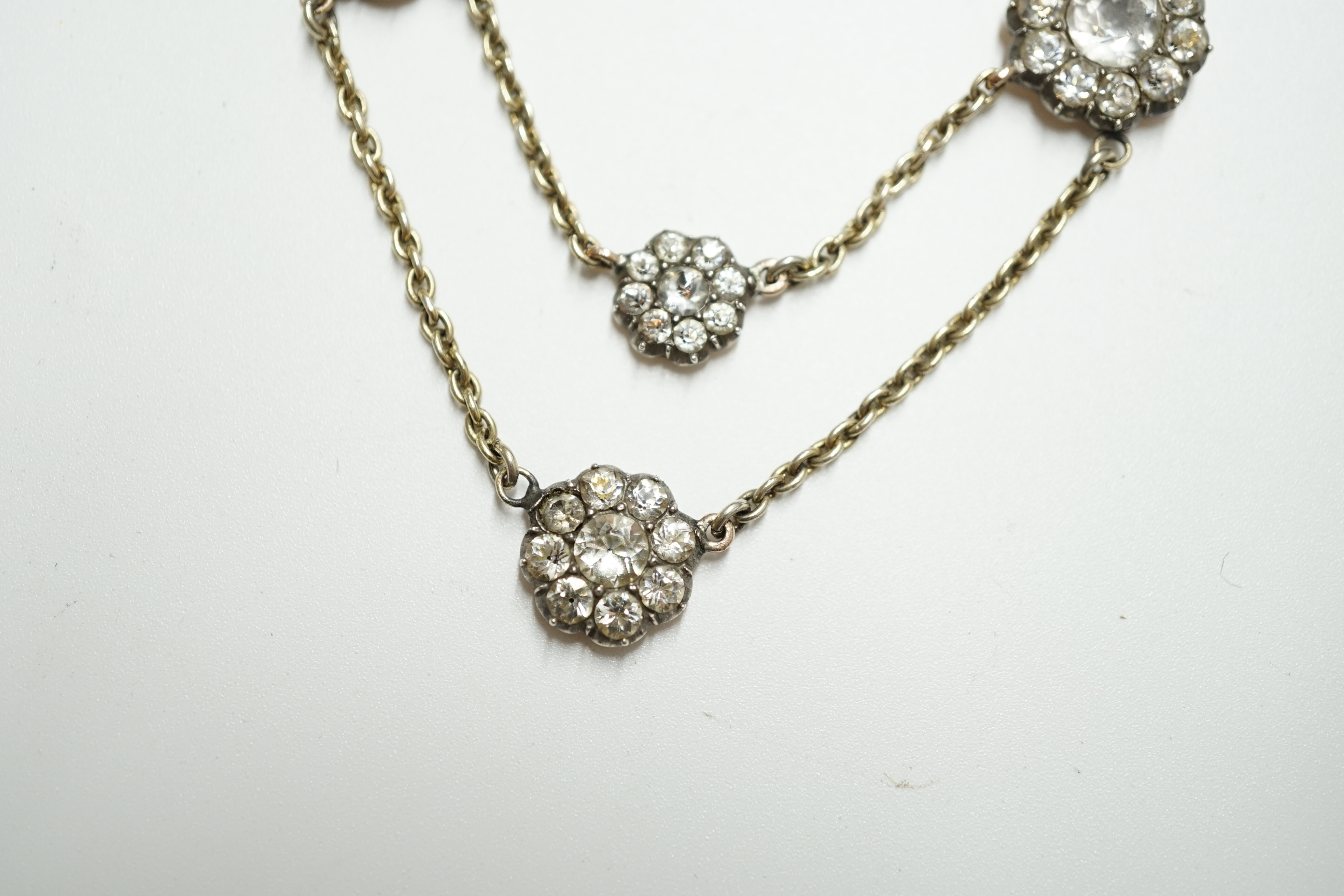 An early 20th century yellow metal and paste set multi flower head necklace, 39cm, gross weight 10.7 grams. Condition - poor to fair
